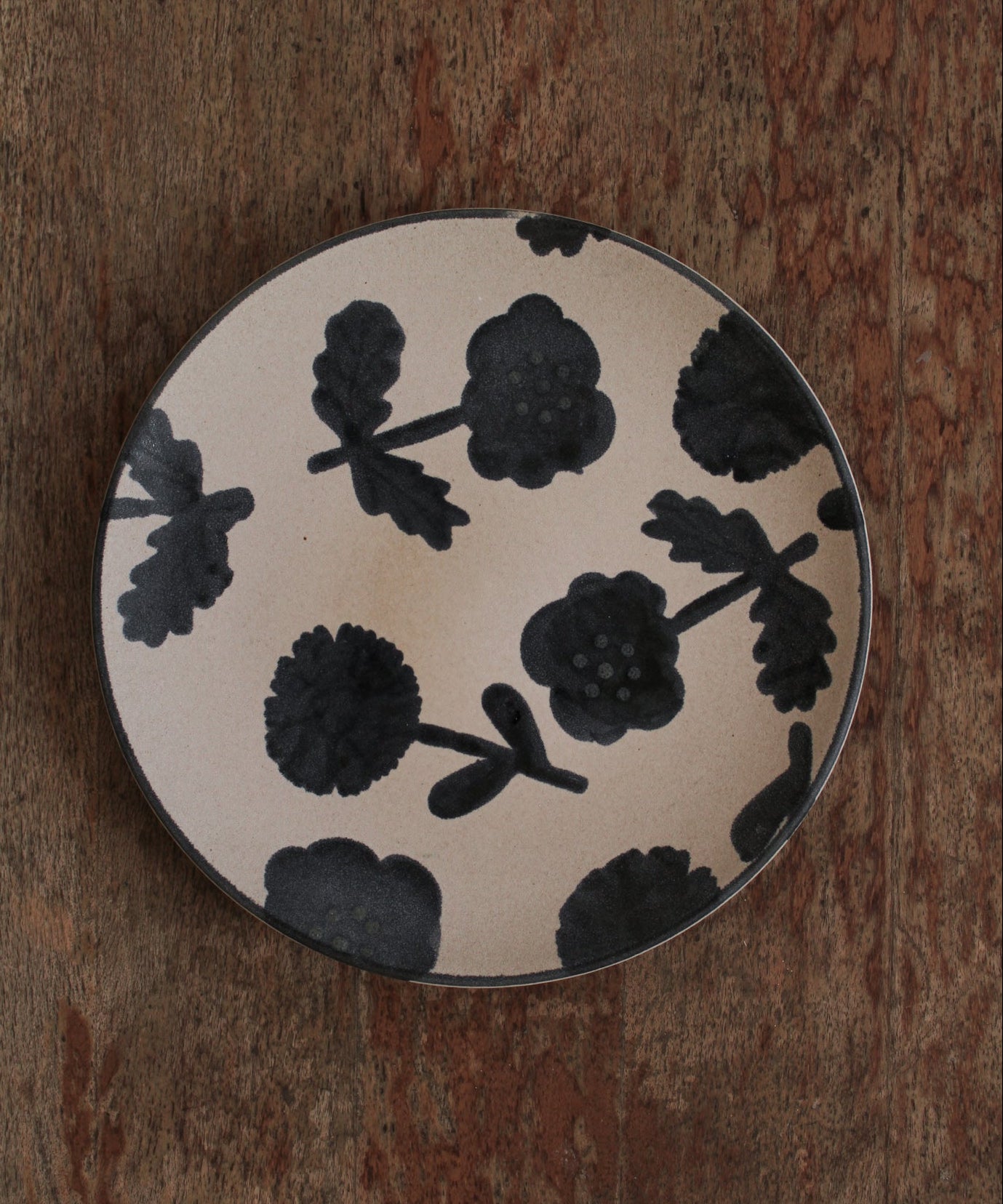 Ceramic plate with black floral design on a wooden surface