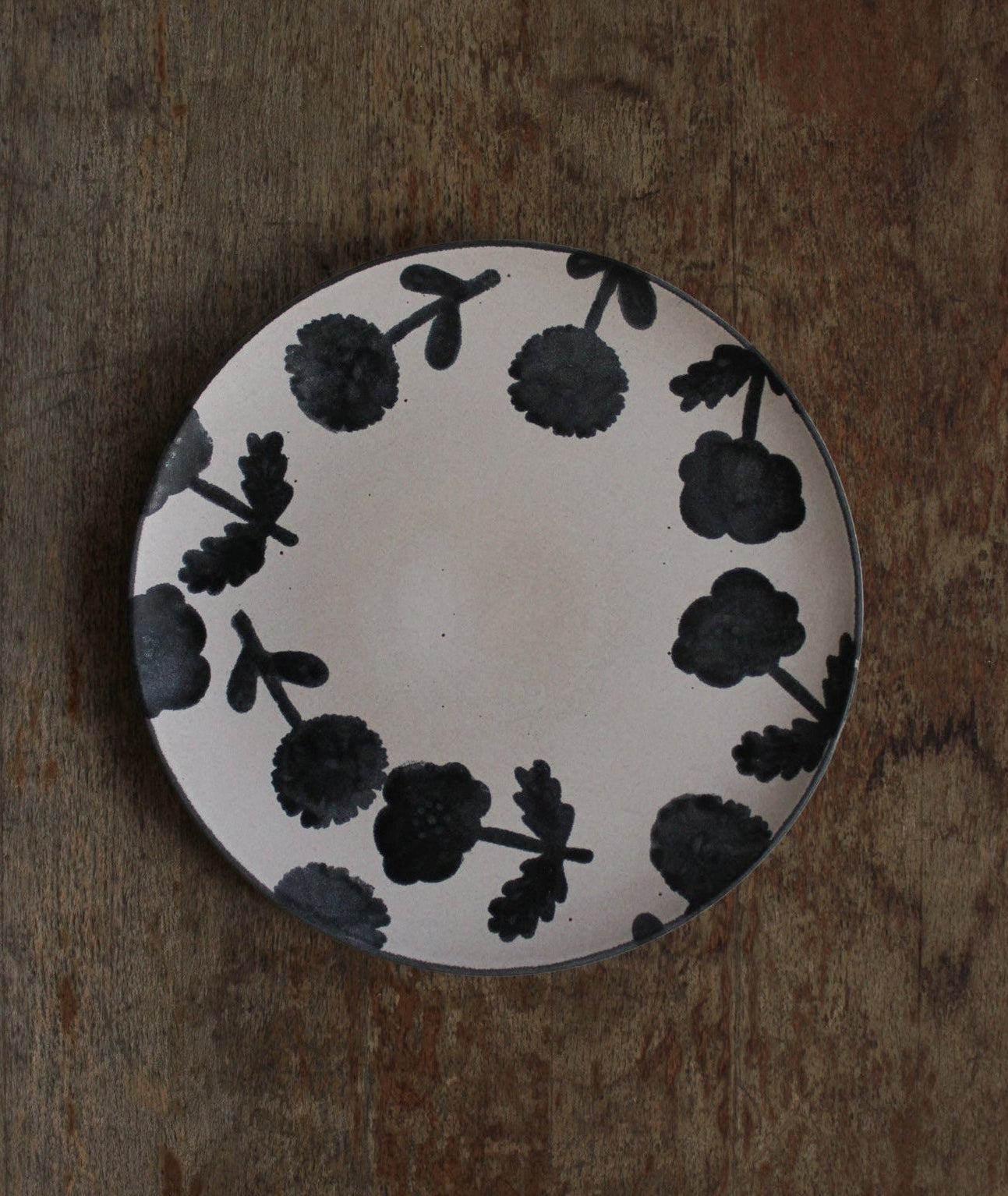 Ceramic plate with black floral pattern on a wooden surface